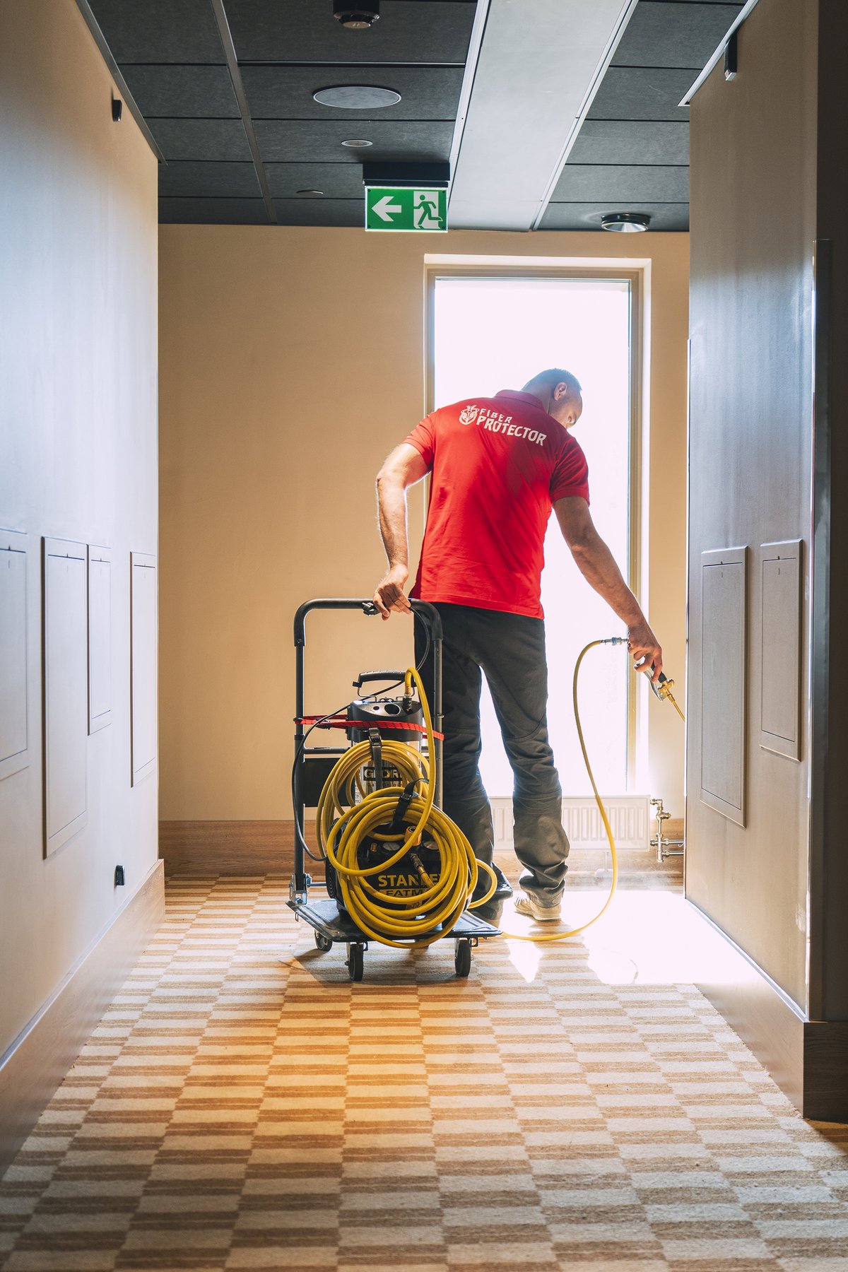 Fiber ProTector-tekniker impregnerer teppe i hotellkorridor