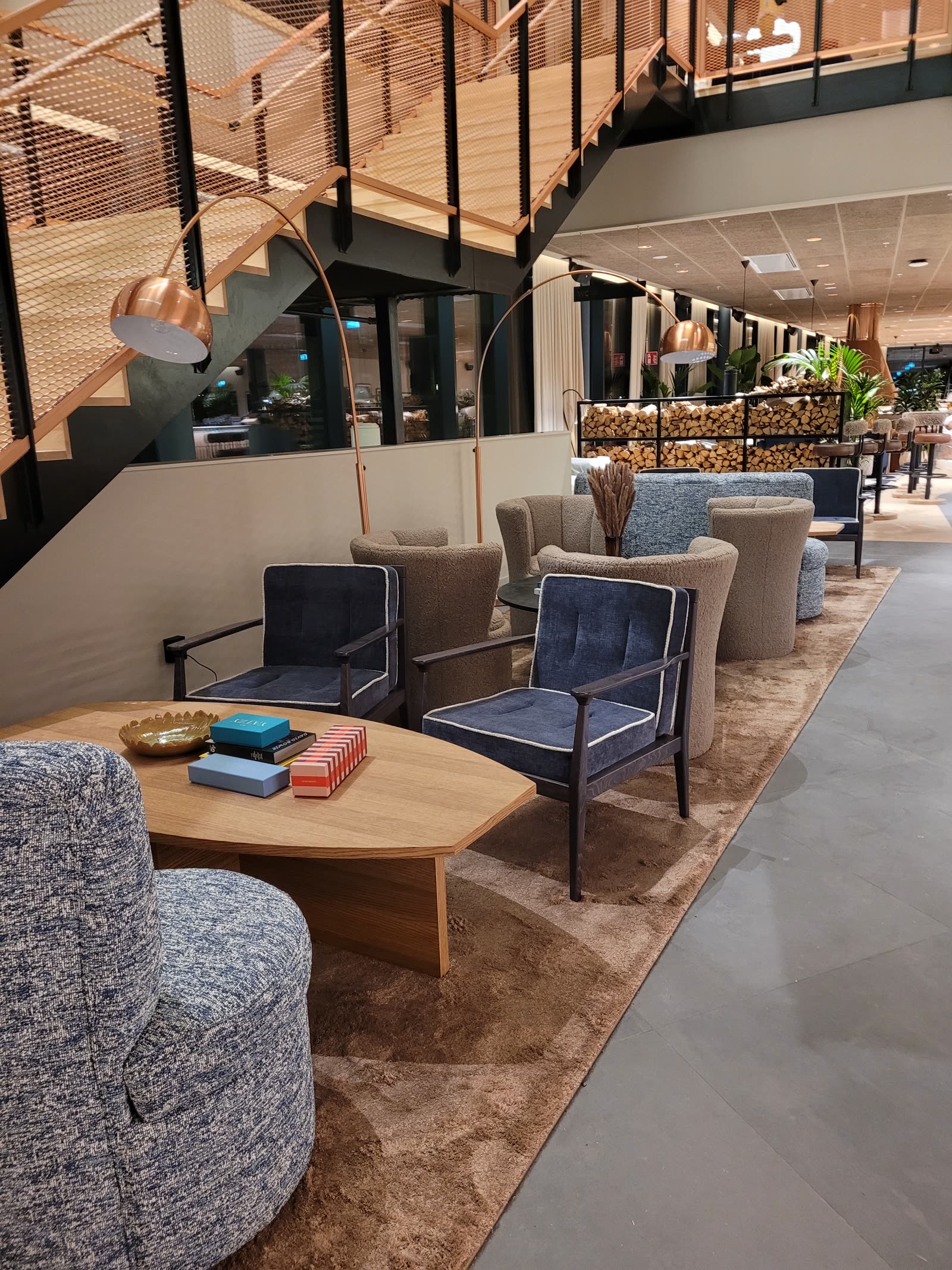 Hotellobby med blå velur-stoler og boucle-sofaer under kobber-lamper