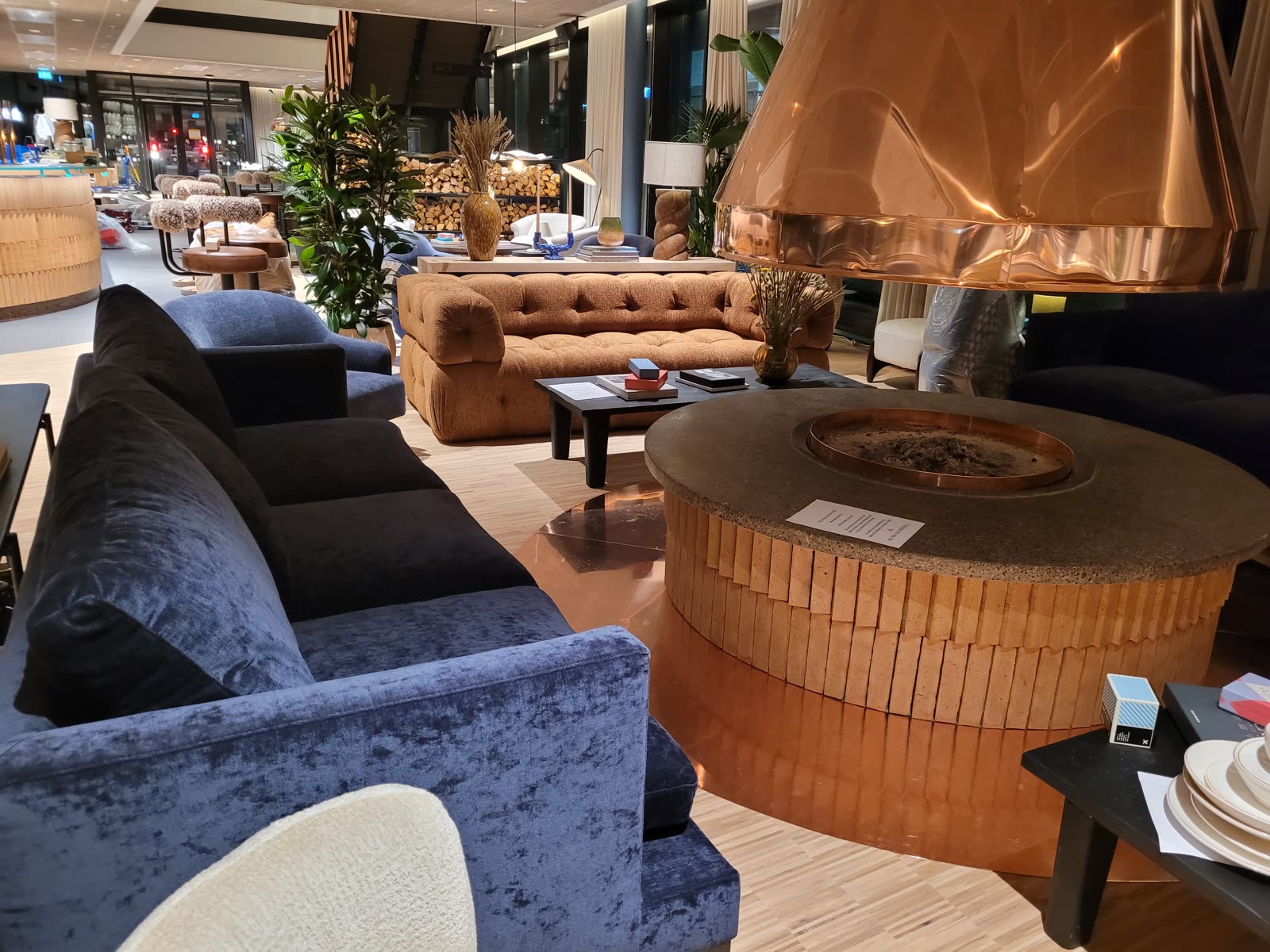 Hotellobby med kobber-peis, blå velur-stoler og fløyelsofa