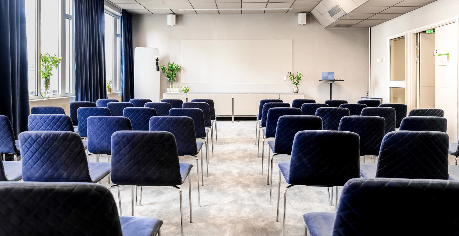 Konferanserom med blå velur-stoler og teppe